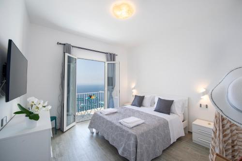 a white bedroom with a bed and a large window at Rays of sun - Positano in Positano