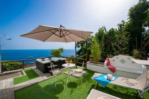 une terrasse avec une table et un parasol et l'océan dans l'établissement Rays of sun - apartment, à Positano