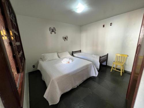 a bedroom with two beds and a yellow chair at POUSADA PALIPALAN in Sao Jorge