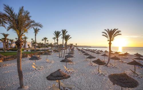 a beach with umbrellas and palm trees and the ocean at Seabel Aladin Djerba in Aghīr