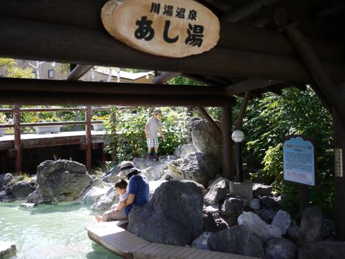 two people sitting on rocks in the water at a zoo at KKR Kawayu in Teshikaga
