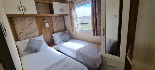 a small room with two beds and a window at Golden Palm Resort - St David - Coastal Caravan Breaks in Chapel Saint Leonards