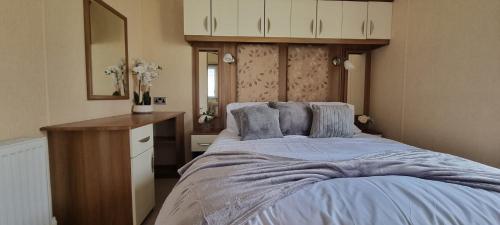 a bedroom with a large bed with a wooden headboard at Golden Palm Resort - St David - Coastal Caravan Breaks in Chapel Saint Leonards