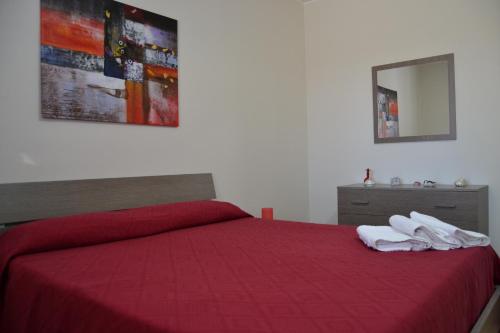 サン・ヴィート・ロ・カーポにあるCasa Mayleaのベッドルーム1室(赤いベッド1台、タオル2枚付)
