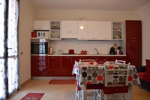 サン・ヴィート・ロ・カーポにあるCasa Mayleaの赤いキャビネットとテーブル付きのキッチンが備わります。
