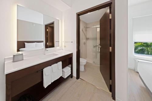 a bathroom with a sink and a toilet and a mirror at Hyatt Place West Palm Beach in West Palm Beach