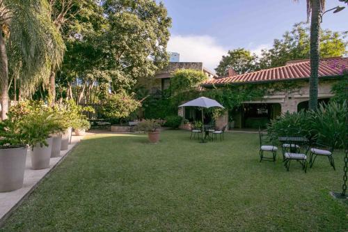 einen Garten mit Stühlen, Tischen und einem Sonnenschirm in der Unterkunft Las Lomas Casa Hotel in Asunción