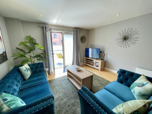 een woonkamer met twee blauwe banken en een tv bij Stunning 2-bed Town Centre Apartment - Hosted by Hutch Lifestyle in Leamington Spa