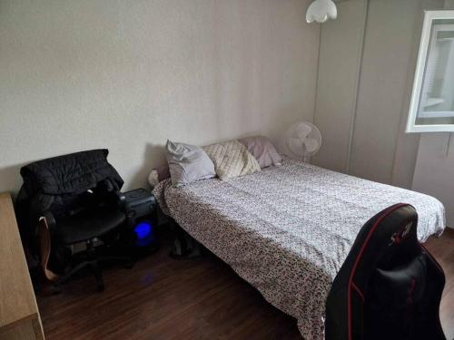 - une chambre avec un lit, une chaise et une valise dans l'établissement Bel appartement centre-ville Ondres - Landes, à Ondres