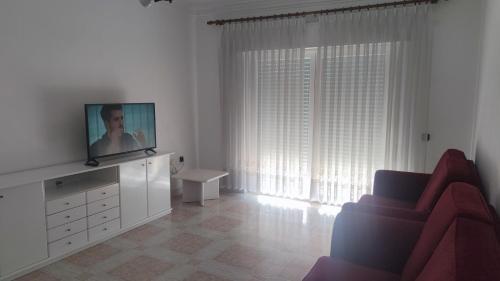 sala de estar blanca con TV y silla en Alojamento das Laranjeiras, en Fernao Ferro
