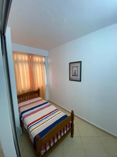 - une chambre avec un lit et une couverture rayée dans l'établissement Holiday Apartaments Durres, à Durrës