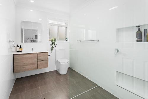 a white bathroom with a toilet and a sink at La Casa Bella in Gerringong