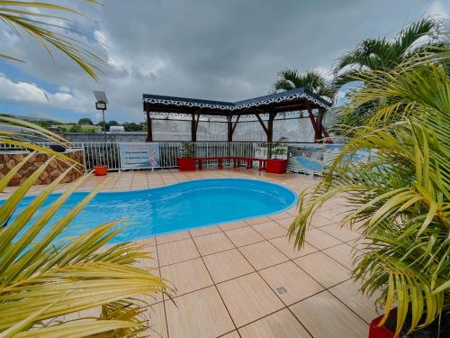 a swimming pool on a patio with a gazebo at Résidence Le Palmier Royal in Sainte-Rose