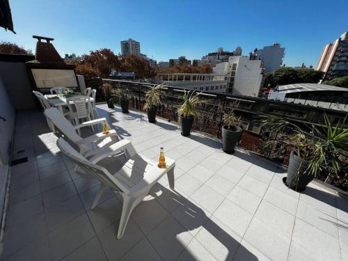 2 sillas blancas y una mesa en el balcón en 2 amb Con rooftop y parrilla propia en Buenos Aires