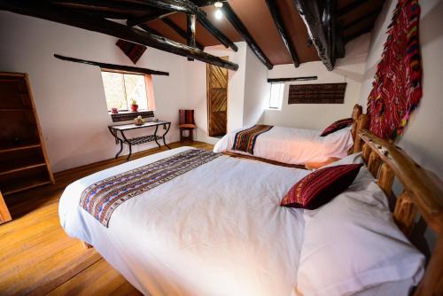 a bedroom with two beds and a table in it at Rumi Lodge Pisac in Pisac