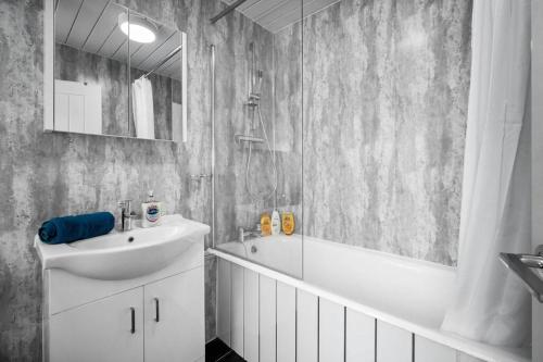 La salle de bains est pourvue d'un lavabo, d'une baignoire et d'un miroir. dans l'établissement 3 bed house/Free parking/contractors/Families, à Bushbury