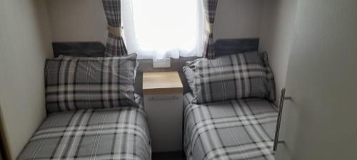 two beds in a small room with a window at Luxury spacious family caravan in Edinburgh