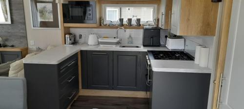 a kitchen with blue cabinets and a stove top oven at Luxury spacious family caravan in Edinburgh