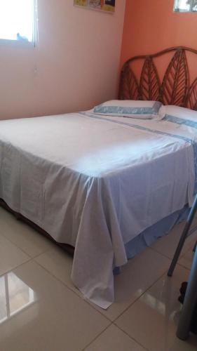 Una cama en una habitación con una manta blanca. en Chácara piscina aquecida, en Cotia
