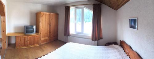 a bedroom with a bed and a tv and a window at Guesthouse Classic in Dospat