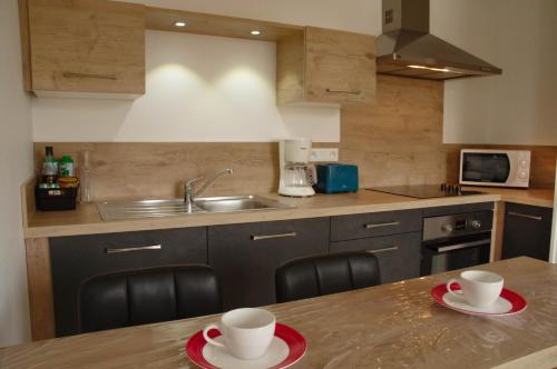 une cuisine avec deux tasses sur une table en bois dans l'établissement Appartement Lisa, à Lézignan-Corbières