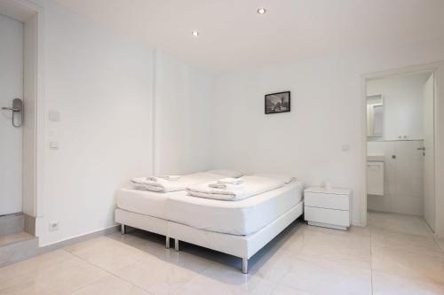 Habitación blanca con cama y espejo en House by StayStay I 24 Hours Check-In, en Núremberg