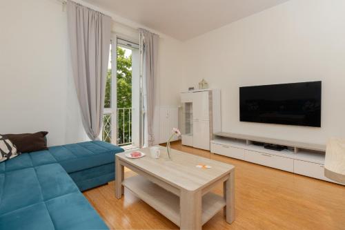 a living room with a blue couch and a table at Cozy Apartment Batalionów Chłopskich in Gdynia by Renters in Gdynia