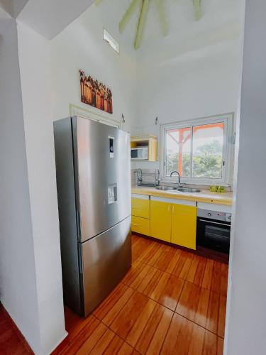 a kitchen with a stainless steel refrigerator and yellow cabinets at Résidence Le Palmier Royal in Sainte-Rose