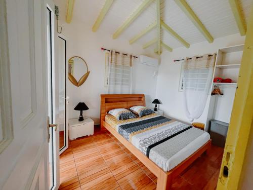 Schlafzimmer mit einem Bett und Holzboden in der Unterkunft Résidence Le Palmier Royal in Sainte-Rose