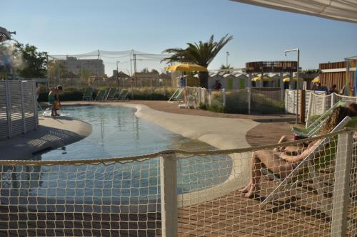 a person sitting in a hammock next to a swimming pool at Hotel Los Angeles - Fronte mare in Riccione