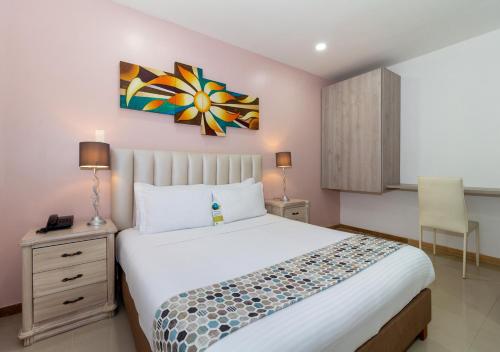 Hotel Costa Bonita في مونتيريا: غرفة نوم بسرير ودهان على الحائط