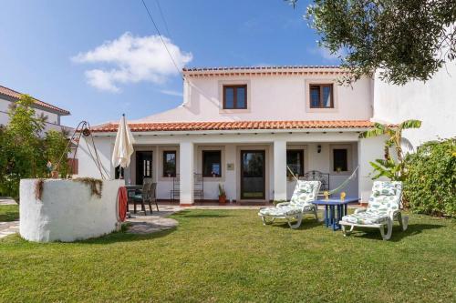 a house with two chairs and a table in the yard at Casa do Moleiro in Caldas da Rainha