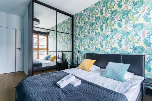 - une chambre avec un lit et du papier peint tropical dans l'établissement Hallera by Loft Apartments, à Gdańsk