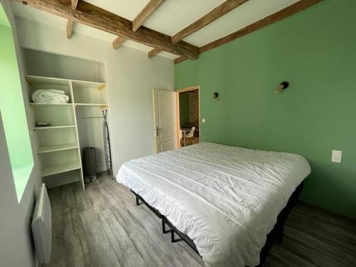 une chambre avec un lit blanc et un mur vert dans l'établissement Au grenier des chevaux - Gîte rénové - Baignoire Balnéo Lac privatif, à Trévien