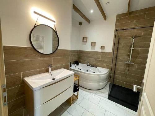 une salle de bain avec un lavabo, un miroir et une baignoire dans l'établissement Au grenier des chevaux - Gîte rénové - Baignoire Balnéo Lac privatif, à Trévien