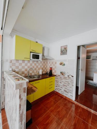 a kitchen with yellow cabinets and a sink at Résidence Le Palmier Royal in Sainte-Rose