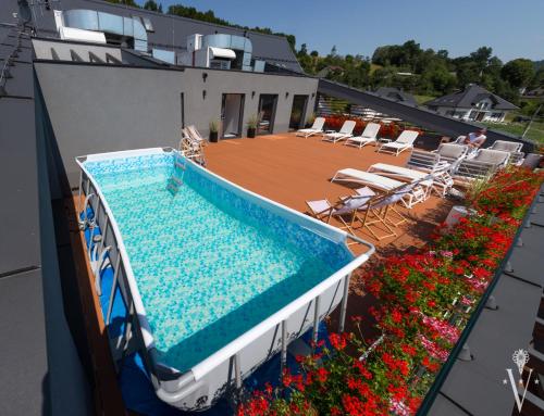 a swimming pool on the roof of a building with chairs and flowers at Hotel Limanova in Limanowa