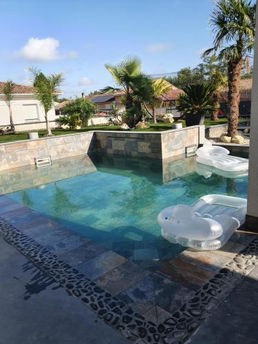 - une piscine avec 2 chaises longues dans l'eau dans l'établissement Villa Caldas, à Sadirac