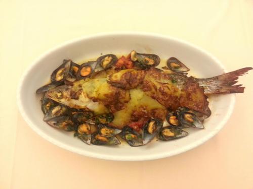 a white bowl of food with a fish and mussels at Hotel Bristol in Lignano Sabbiadoro