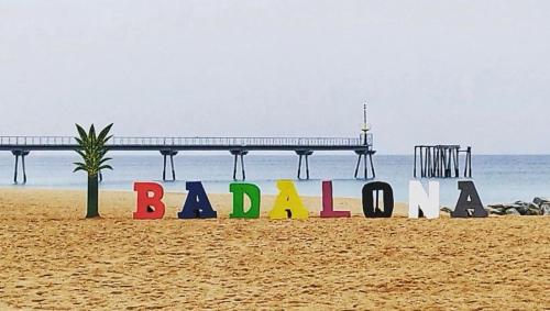 a sign on a beach with a pier in the background at CasaBala - Near the beach and Barcelona center in Badalona