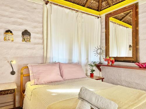 a bedroom with a bed and a mirror at Casas D'Água Doce - Casa Cachoeira. in Ilhabela