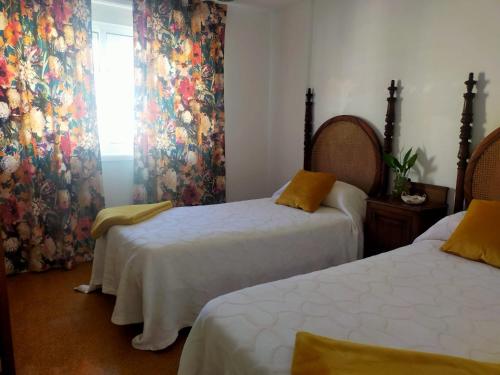 um quarto com duas camas e uma janela em Cerca de la playa, con bodega, terraza y jardin Camino Portugués em A Guarda