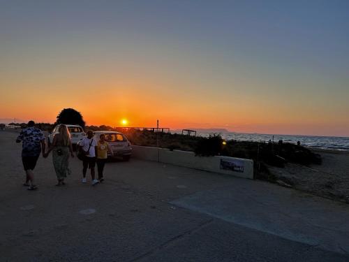 a group of people walking on the beach at sunset at La Casa di Leone Casa Sorella in Svoúrou Metókhion