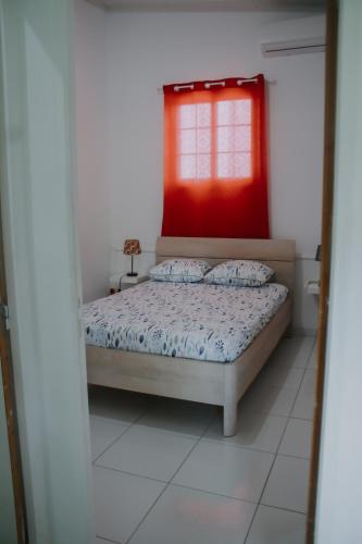 a bedroom with a bed and a red window at Résidence Le Palmier Royal in Sainte-Rose