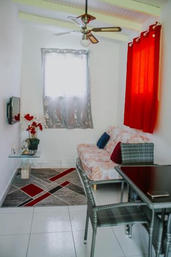 a living room with a couch and red curtains at Résidence Le Palmier Royal in Sainte-Rose