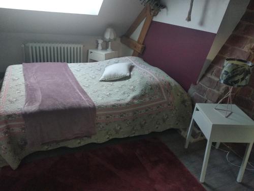 Schlafzimmer mit einem Bett mit einem Kissen und einem Tisch in der Unterkunft Suite familiale Mamito et Papito in Notre-Dame-du-Bec