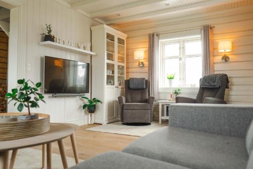a living room with a couch and chairs and a tv at Lofoten Villa in Reine