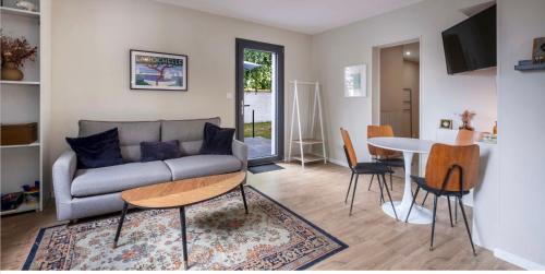 - un salon avec un canapé et une table dans l'établissement Appartement Les Camélias proche La Rochelle, à Périgny