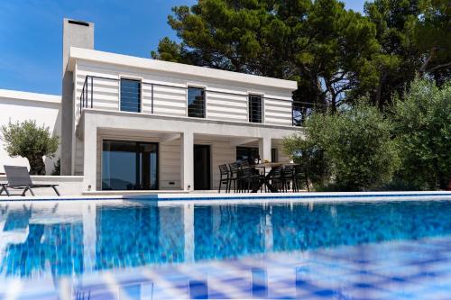 a white house with a swimming pool in front of it at Seaside luxury villa with a swimming pool Sumartin, Brac - 5639 in Sumartin
