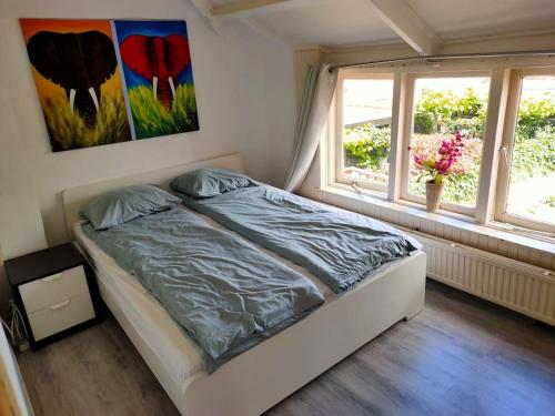 a bedroom with a bed and a painting on the wall at Nice House with a garden in the centre near the sea and Amsterdam in Beverwijk